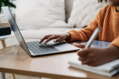 Hands of girl using laptop and doing homework at home