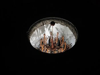 Low angle view of illuminated lighting equipment against black background