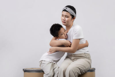 Mother and daughter standing against white background