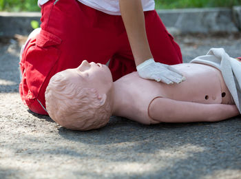 Midsection of paramedic performing cpr on dummy