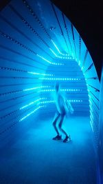 Low angle view of woman walking in illuminated tunnel