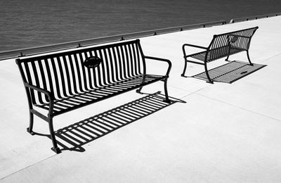 High angle view of empty chairs on pier against sea