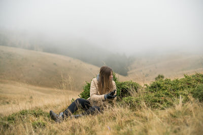 Man sitting on field against sky