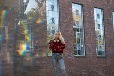 Portrait of young woman standing against buildings