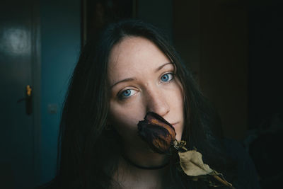 Close-up portrait of young woman holding dried rose