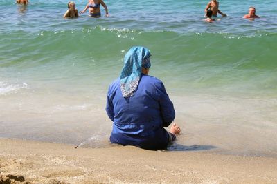 Rear view of woman sitting in water