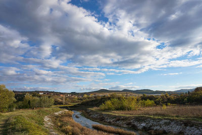 Scenic view of road amidst field against sky