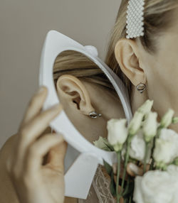 Blonde girl with a beautiful elegant stylish silver earring, pearl hairpin, mirror