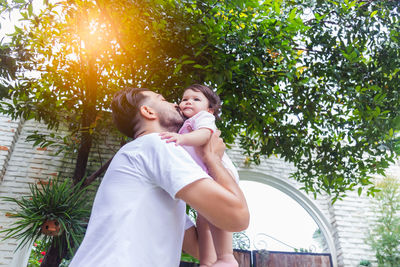 Couple kissing against trees and plants