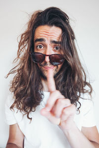 Young hipster long haired bearded male in sunglasses with funny amazed face expression looking at camera while taking selfie