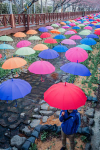 Man with umbrella walking on multi colored umbrellas