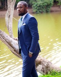 Portrait of man wearing suit standing against lake