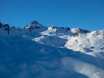 Scenic view of snowcapped mountains against clear blue sky