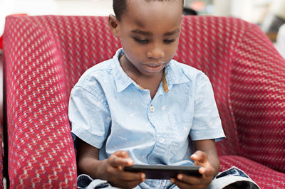 This child is very focus on his game in the mobile phone.