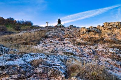 Rocks and trees on rock against sky