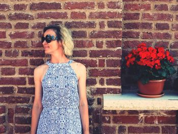 Portrait of young woman standing against wall