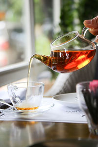 Close-up of hand pouring tea in glass