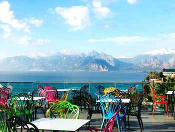 Chairs and tables at beach against sky