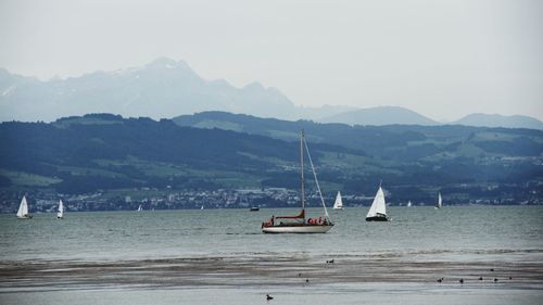 Boats in sea with mountain range in background