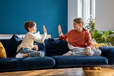 Side view of woman using mobile phone while sitting on sofa at home