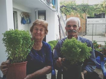 Portrait of smiling woman holding potted plants