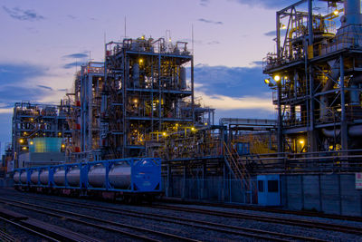 Illuminated factory against sky at dusk