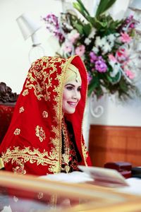 Portrait of young woman smiling and sitting on table in minangkabau traditional wedding ceremony