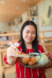 Portrait of a smiling young woman holding food