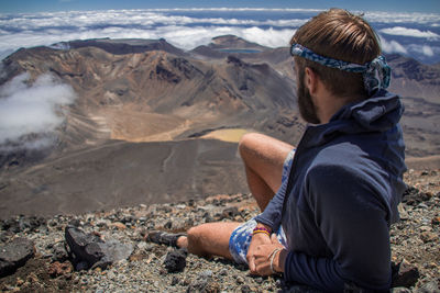 Rear view of man sitting on mountain