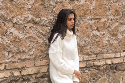 Young woman standing against wall