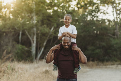 Close up portrait of school-aged son sitting on father's shoulders