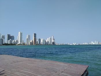 Sea by buildings against clear sky