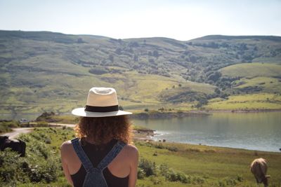 Rear view of woman looking at lake against mountain range