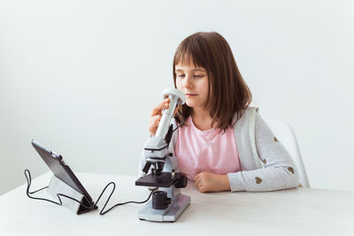 Woman using mobile phone while sitting on table