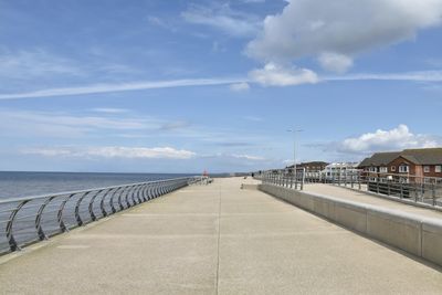 Footpath by sea against sky