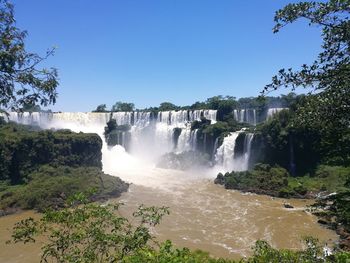 Scenic view of waterfall in forest against clear sky