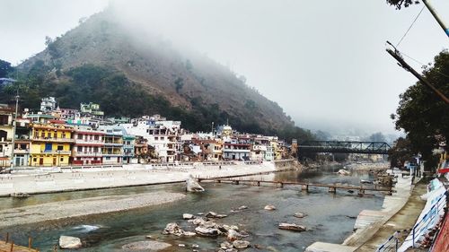 Buildings by river in city against sky