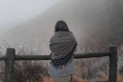 Rear view of woman standing on railing against mountain