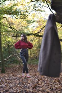 Full length of woman with hands on hip standing in forest