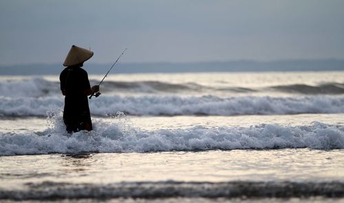 Rear view of fisherman at beach