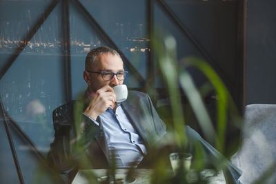 Businessman drinking coffee on table sitting in cafe