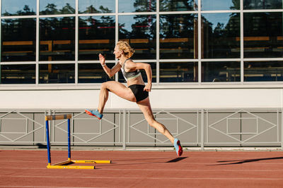 Female athlete run 400 meters hurdles in athletics at stadium