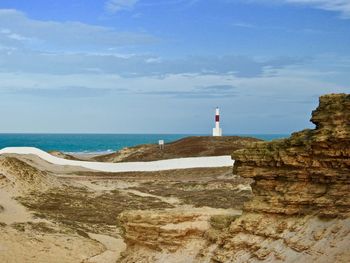 Lighthouse by sea against sky