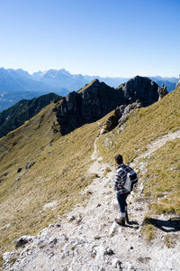 Rear view of man standing on mountain against clear sky
