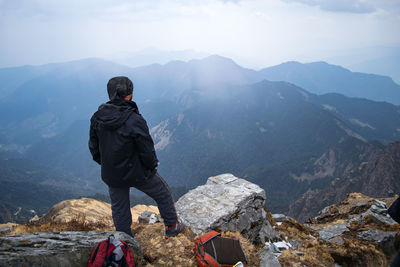 Rear view of man looking at mountains against sky