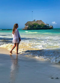 Full length of woman walking on beach against sky