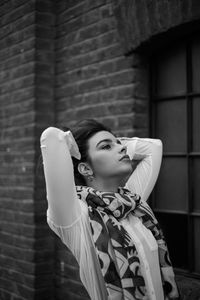 Portrait of young woman looking away against wall