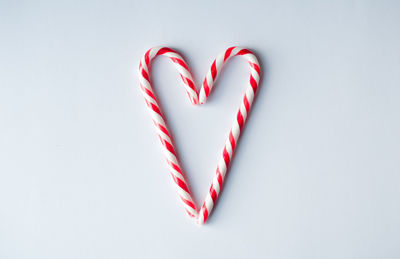 Candy canes arranged in a heart shape on a plain white background.