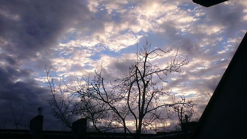 Low angle view of bare tree against cloudy sky