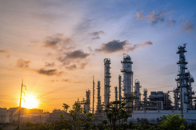 Chemical oil refinery plant, power plant and metal pipe on sunrise sky background.